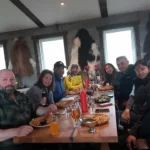 Group of friends seated around a long table enjoying a meal and drinks inside a cozy Icelandic restaurant.