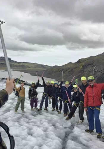 Group of glacier hikers raising ice axes on an Iceland glacier.
