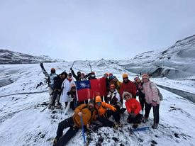 Hikers in helmets and winter gear stand on the snowy Sólheimajökull glacier with ridges of ice behind them.