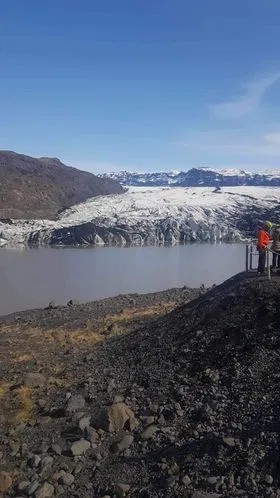 View of Sólheimajökull glacier across a calm glacial lagoon.