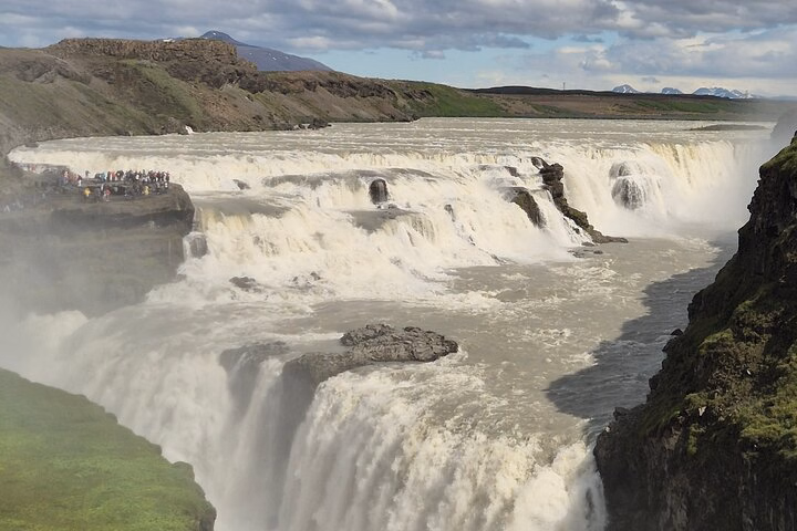 Wide view of Gullfoss with powerful, multi-tiered falls and mist rising from the gorge.